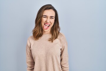 Young woman standing over isolated background sticking tongue out happy with funny expression. emotion concept.