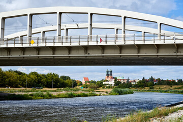 Obraz premium The steel structure of the bridge over the Warta River overlooking the Gothic cathedral
