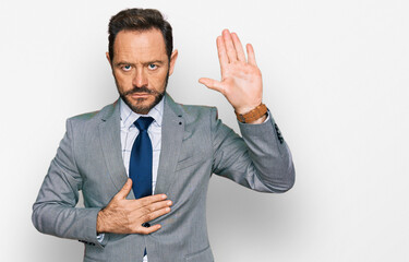 Middle age man wearing business clothes swearing with hand on chest and open palm, making a loyalty...