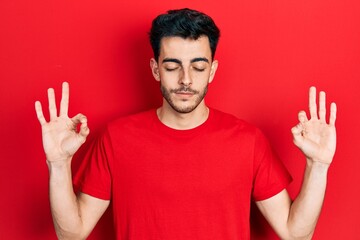 Fototapeta premium Young hispanic man wearing casual clothes relax and smiling with eyes closed doing meditation gesture with fingers. yoga concept.