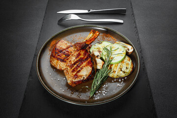 Grilled juicy pork steak with vegetables, BBQ dishes. Black background. Front view