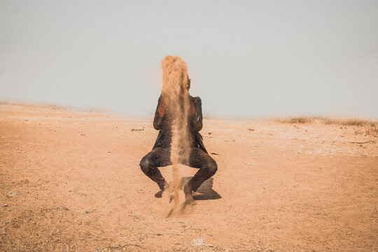 African man throwing brown sand in desert