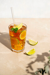 Iced tea with lemon, fresh mint leaves and ice in tall glasses with sun light and shadows.