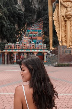 Back view of young woman at the exterior of Batu Caves in Gombak, Selangor, Malaysia