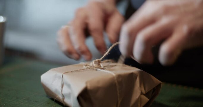 Male artisan wrapping parcel on table