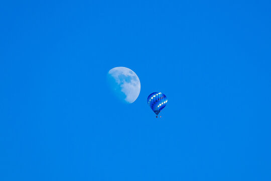 Fototapeta Blue hot air balloon floating on blue sky near gibbous moon