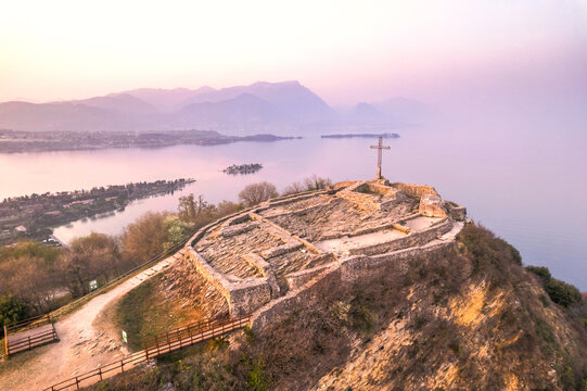 Aerial view of fortress with a cross on a hill in the background Lake Garda. Panorama on the rocca di manerba top view.