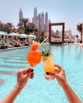 Cropped image of hands holding cocktail near swimming pool