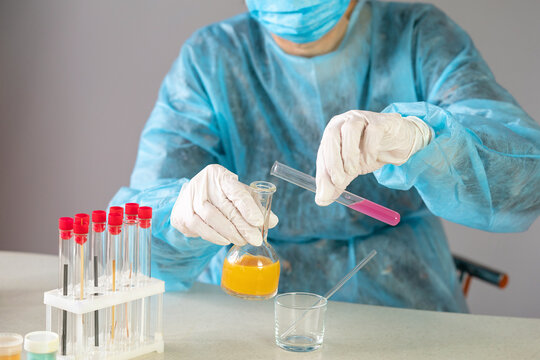 Cropped image of healthcare worker sitting at a table holding testing tubes