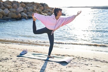Young woman training yoga exercise standing at seaside