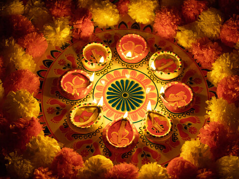 Diwali Rangoli with lit diyas and marigold flowers