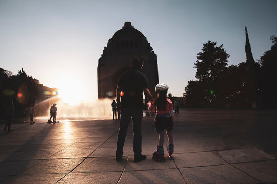 Father and daughter in a roller shoes and helmet  standing on a concrete floor