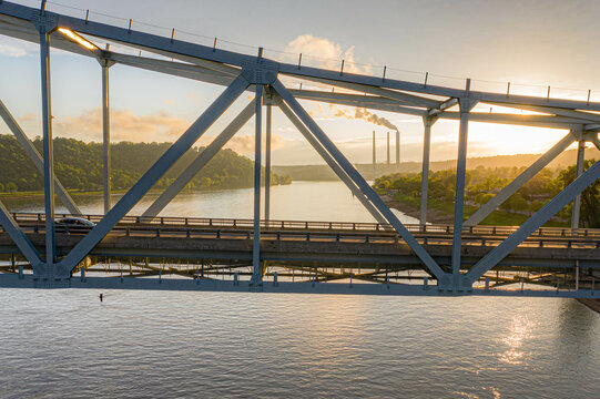 Gray metal train bridge over river at sunset