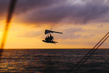 Fototapeta na wymiar An hang glider flies over the sea at sunset. Summer activities. Sport. High quality photo