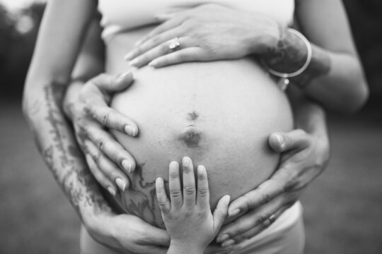 Grayscale photo of pregnant woman holding her tummy