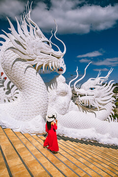 Lady in red dress and fedora hat walking around Wat Huay Pla Kang in Chiang Rai, Chiang Mai province, Thailand