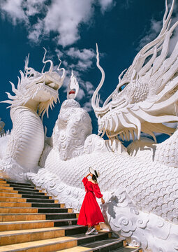 Lady in red dress and fedora hat walking around Wat Huay Pla Kang in Chiang Rai, Chiang Mai province, Thailand