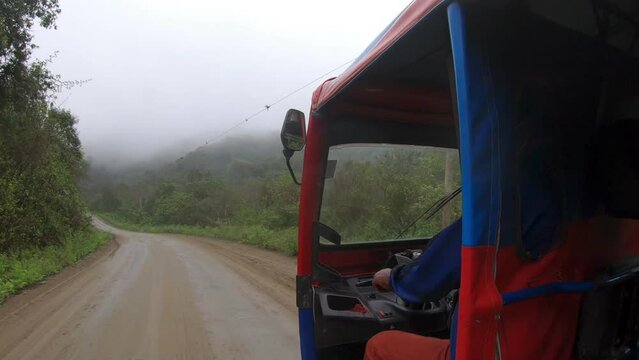 Side view of a auto rickshaw driving along a road.