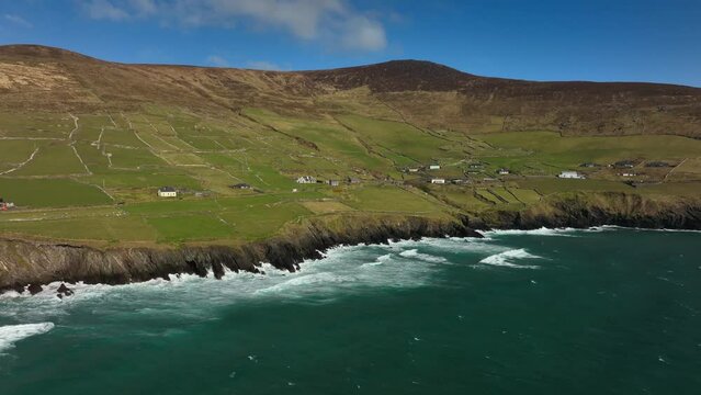 Coumeenoole Bay, Kerry, Ireland, March 2022. Drone tracks northwest along the craggy shoreline at Dunmore head tracking along the Dingle Way with Ventry in the background.