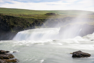 Flowing water near the edge of a majestic waterfall. Power in nature concept. Godafoss waterfall, Iceland.