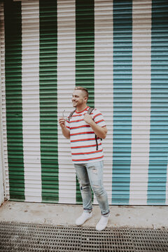 Man in red stripe shirt standing beside green roller shutter door