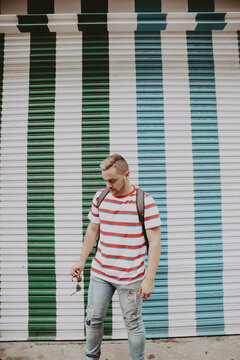 Man in red stripe shirt standing beside green roller shutter door