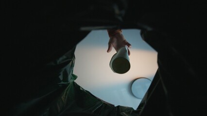 Hand putting paper cup in recycling bin. Bottom view from the trash bin. Ecology concept. 