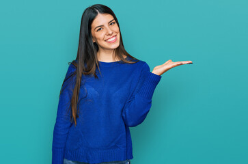 Young hispanic woman wearing casual clothes smiling cheerful presenting and pointing with palm of hand looking at the camera.