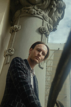 Mature man in plaid blazer posing beside pillar