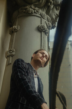 Mature man in plaid blazer posing beside pillar