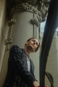Mature man in plaid blazer posing beside pillar