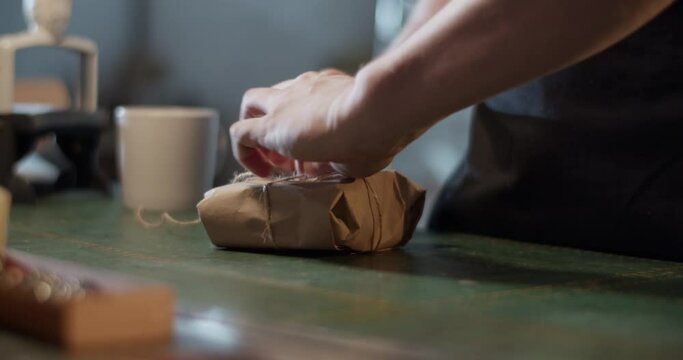 Male artisan wrapping parcel on table