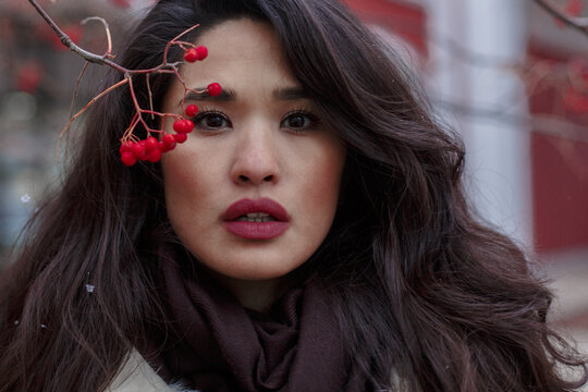 Portrait of East Asian woman beside red tree berries