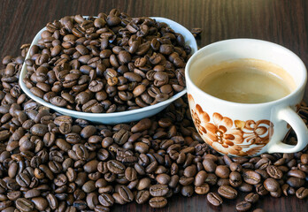 A cup of coffee and a bowl with coffee beans