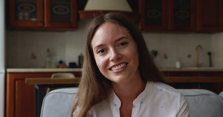 Close up head shot portrait young woman make videocall talks to family remotely. Millennial female sit on sofa at home use videoconference app having pleasant conversation. Video call event concept