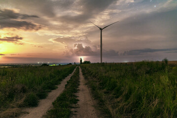 Photograph of large wind turbines in a row in the meadow during a lightning storm