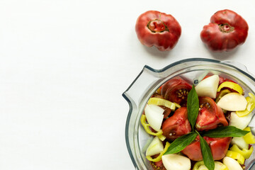 Top view of plastic mixer cup with vegetables to make fast tomato sauce.