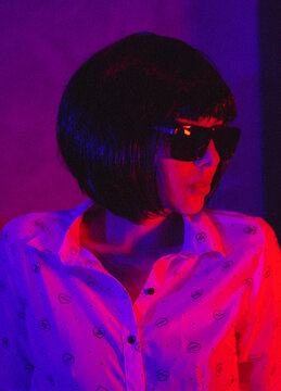 Portrait Of Young Woman With Sunglasses And Short Hair Wig In Red Lit Studio