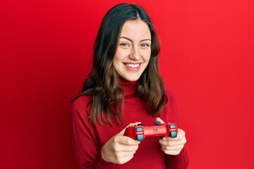 Young brunette woman playing video game holding controller smiling with a happy and cool smile on face. showing teeth. © Krakenimages.com