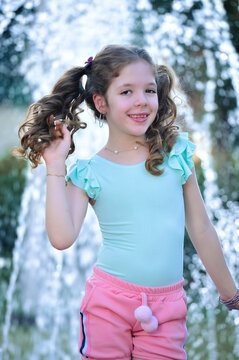 Smiling girl wearing blue blouse and pink short standing outdoor