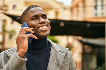 Young african american man smiling happy talking on the smartphone at the city