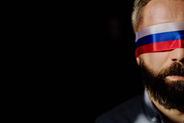 Man with Russian flag blindfold on black background, Russian propaganda closed people's eyes...