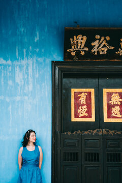 Woman in blue dress standing beside brown wooden door