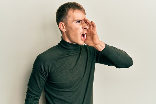 Young caucasian man wearing casual clothes shouting and screaming loud to side with hand on mouth. communication concept.