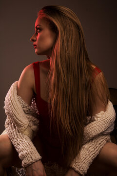 Woman in red top and light sweater sitting and looking sideway