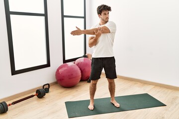 Young hispanic man stretching at sport center