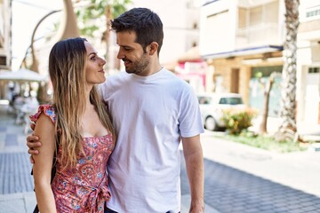 Obraz premium Young hispanic couple hugging in love at the city. Girlfriend and boyfriend together in love walking on the street