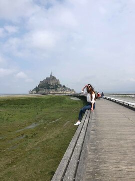 Woman siting on gray wooden bridge near Mont Saint-Michel in France