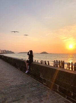Woman sitting near sea at sunset