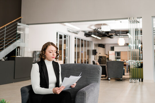 Woman sitting inside office reading papers